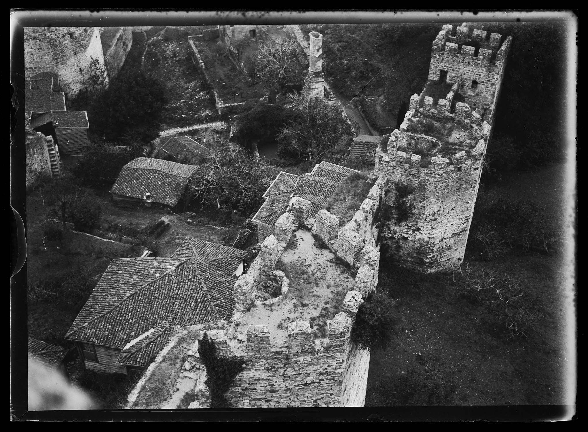 Vue de la partie haute d'une courtine et de maisons à l'intérieur du château